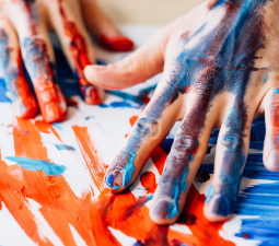 Zwei Hände malen einabstraktes Bild mit Fingerfarben