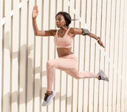 Eine Frau im sportlichen Outfit springt beim Laufen in die Luft